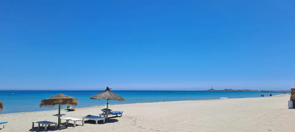 Playa con sombrillas bajo un cielo azul